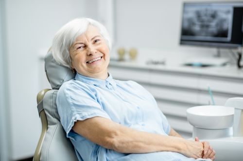 Smiling elderly woman in a dental chair at The Village Dental, Pinecrest, FL, showcasing a comfortable and welcoming dental experience.