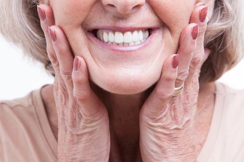 Smiling older woman with well-maintained teeth, showcasing the results of restorative dentistry at The Village Dental in Pinecrest, FL, emphasizing natural aesthetics and patient satisfaction.