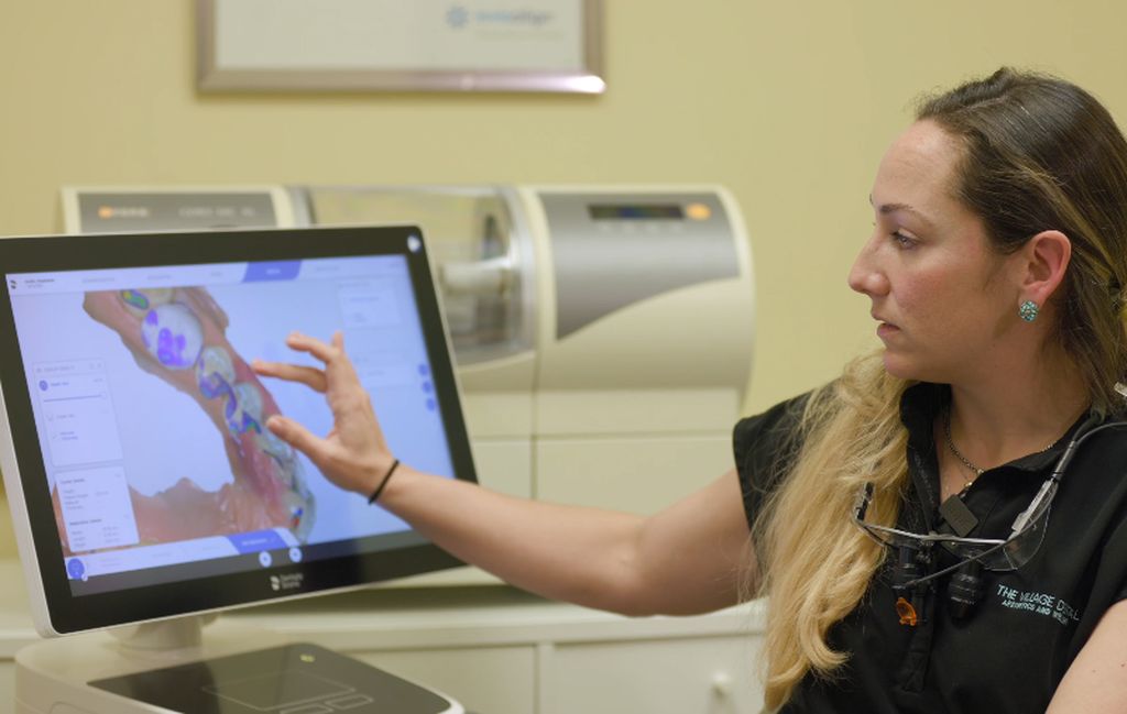 Dentist at The Village Dental in Pinecrest, FL, demonstrating orthodontic treatment options on a digital screen, showcasing advanced dental technology for personalized care.