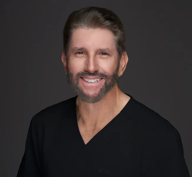 Dr. Robert Kaufman, dentist at The Village Dental in Pinecrest, FL, smiling in professional attire, showcasing a welcoming demeanor for patients seeking general and cosmetic dentistry.