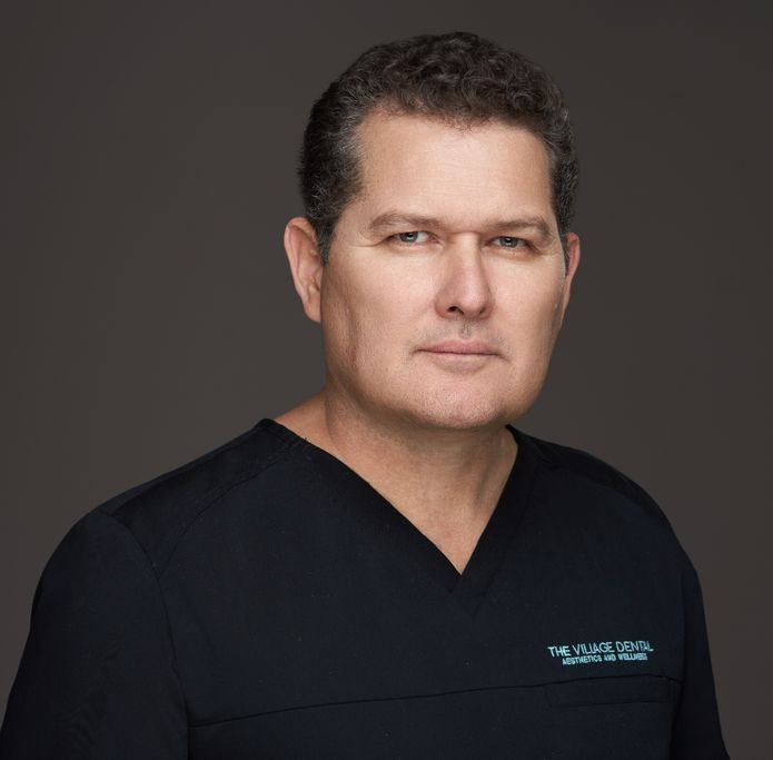 Juan Garcia, dental assistant at The Village Dental in Pinecrest, FL, wearing a black dental scrubs, showcasing a professional demeanor, emphasizing patient care and wellness in dentistry.