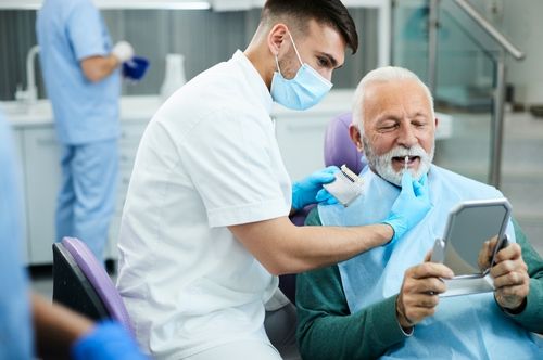 Dentist assisting senior patient with dental care, showcasing a relaxed atmosphere at The Village Dental in Pinecrest, FL, emphasizing restorative dentistry and personalized service.