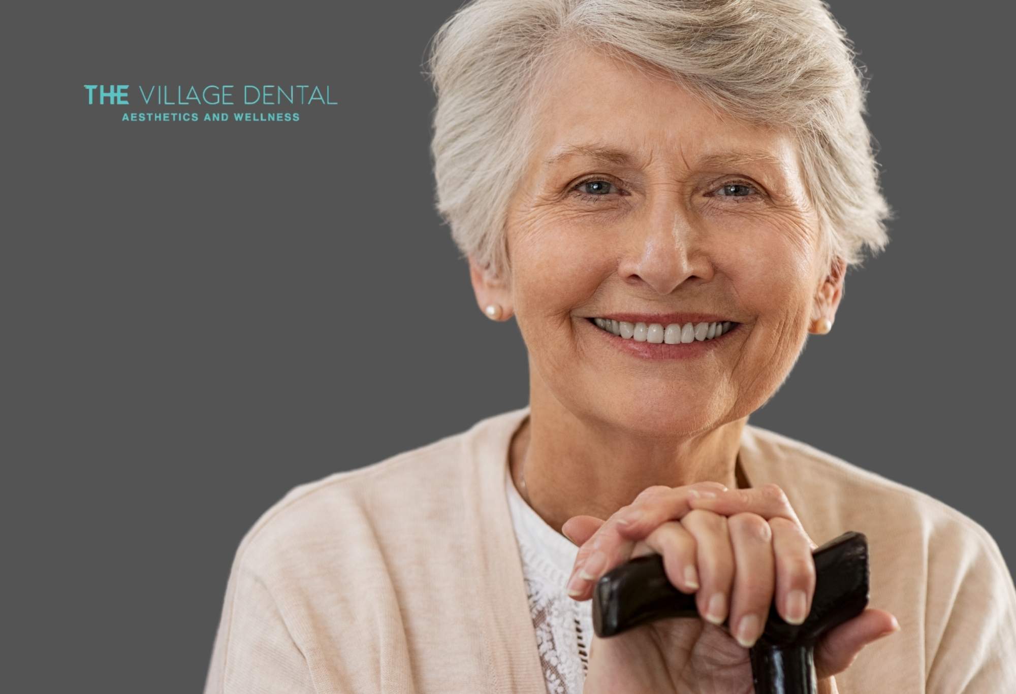 Smiling older woman holding a cane, showcasing a natural-looking smile after dental restoration at The Village Dental in Pinecrest, FL.
