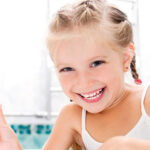 Smiling young girl after a dental visit at The Village Dental, showcasing a positive experience in Pinecrest, FL, emphasizing healthy smiles and patient care.