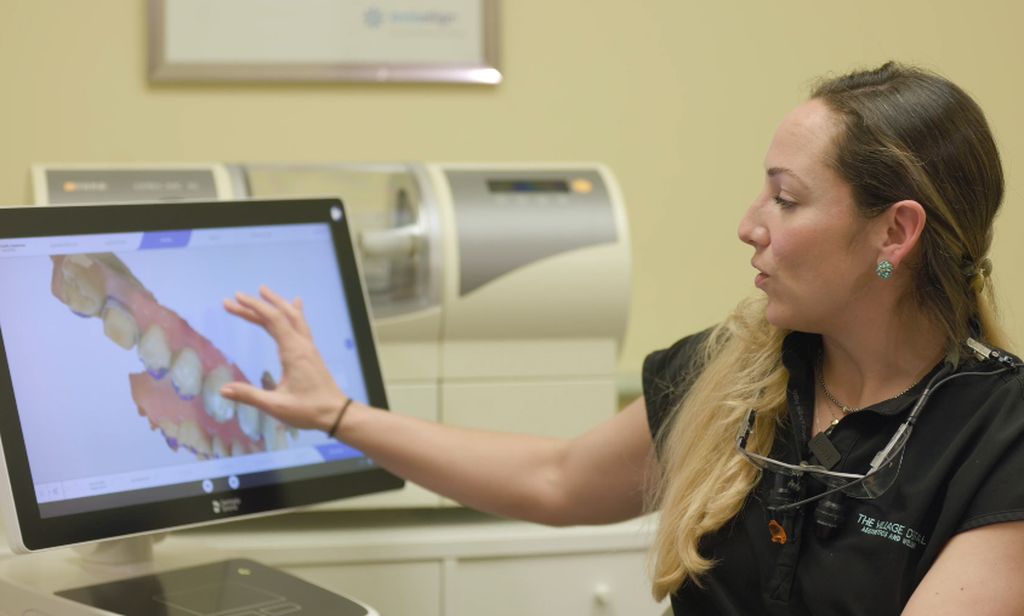 Dental professional at The Village Dental in Pinecrest, FL, demonstrating advanced dental technology on a screen, showcasing personalized treatment options for patients.