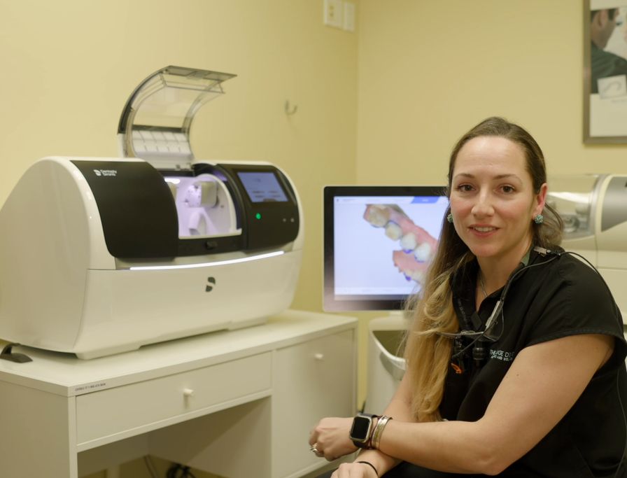 Dental professional at The Village Dental in Pinecrest, FL, with advanced dental technology, including a CAD/CAM machine for same-day crowns, enhancing patient care and comfort.