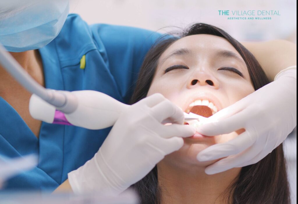 Patient receiving root canal treatment at The Village Dental, with a dentist in blue scrubs performing the procedure, showcasing a calm and professional dental environment in Pinecrest, FL.