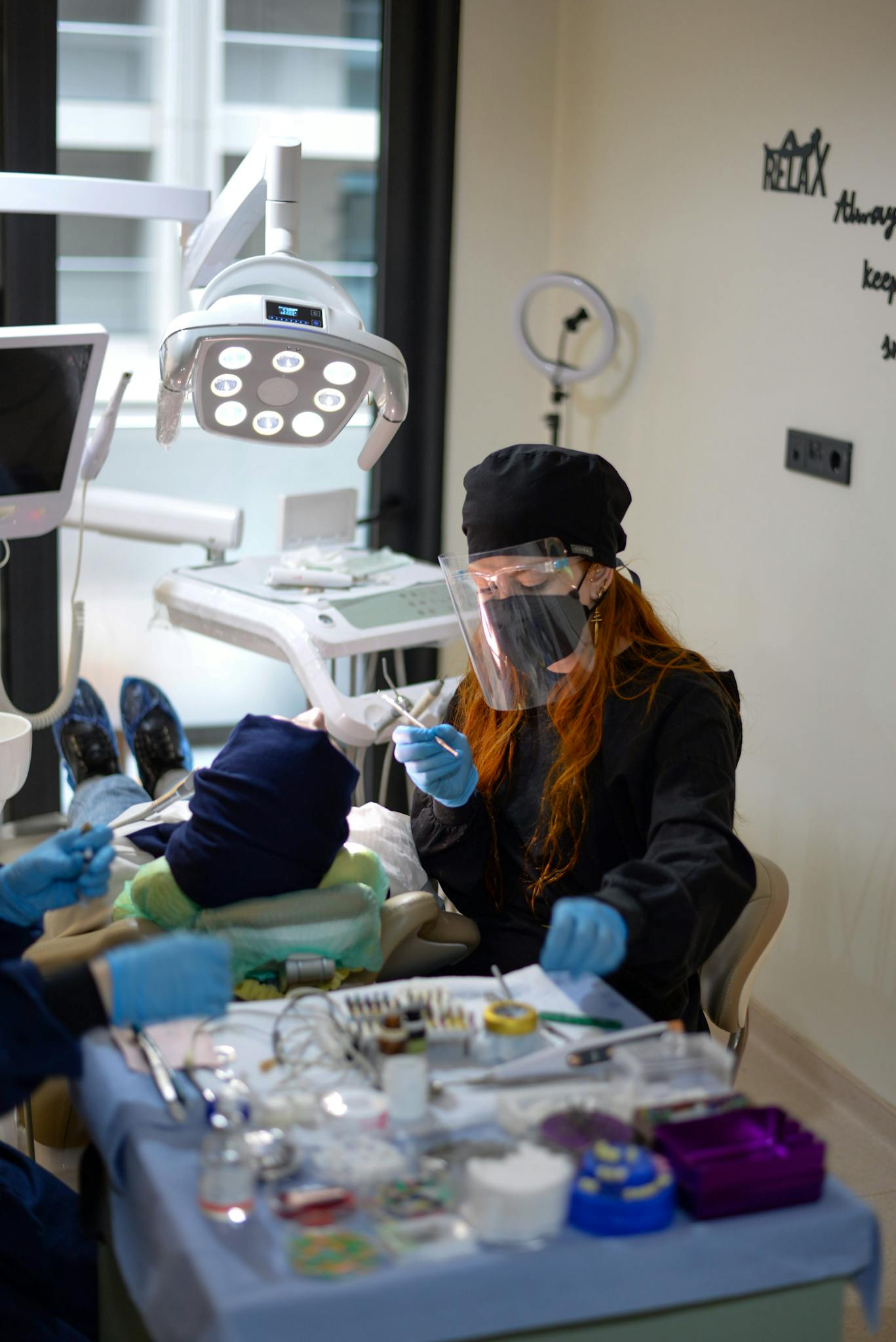 Female dentist in protective gear providing dental care in a modern clinic, showcasing a calm and professional environment at The Village Dental, Pinecrest, FL.
