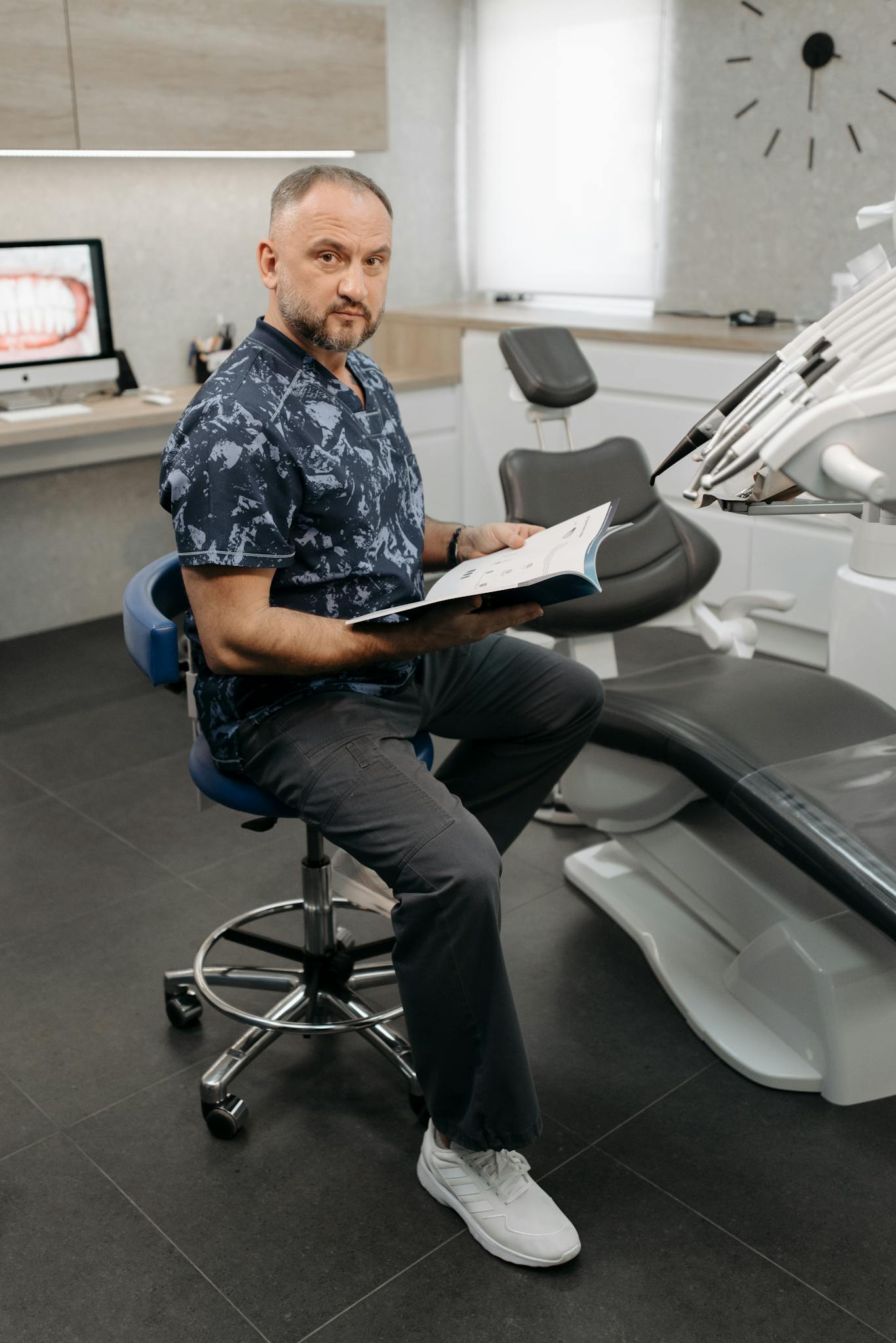 Dentist seated in a modern clinic reviewing patient information, reflecting The Village Dental's commitment to personalized cosmetic and restorative dentistry in Pinecrest, FL.