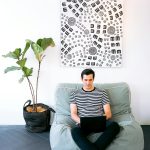Man sitting comfortably on a couch, using a laptop in a relaxed environment, reflecting the calm and professional atmosphere of The Village Dental's cosmetic dental services in Miami.